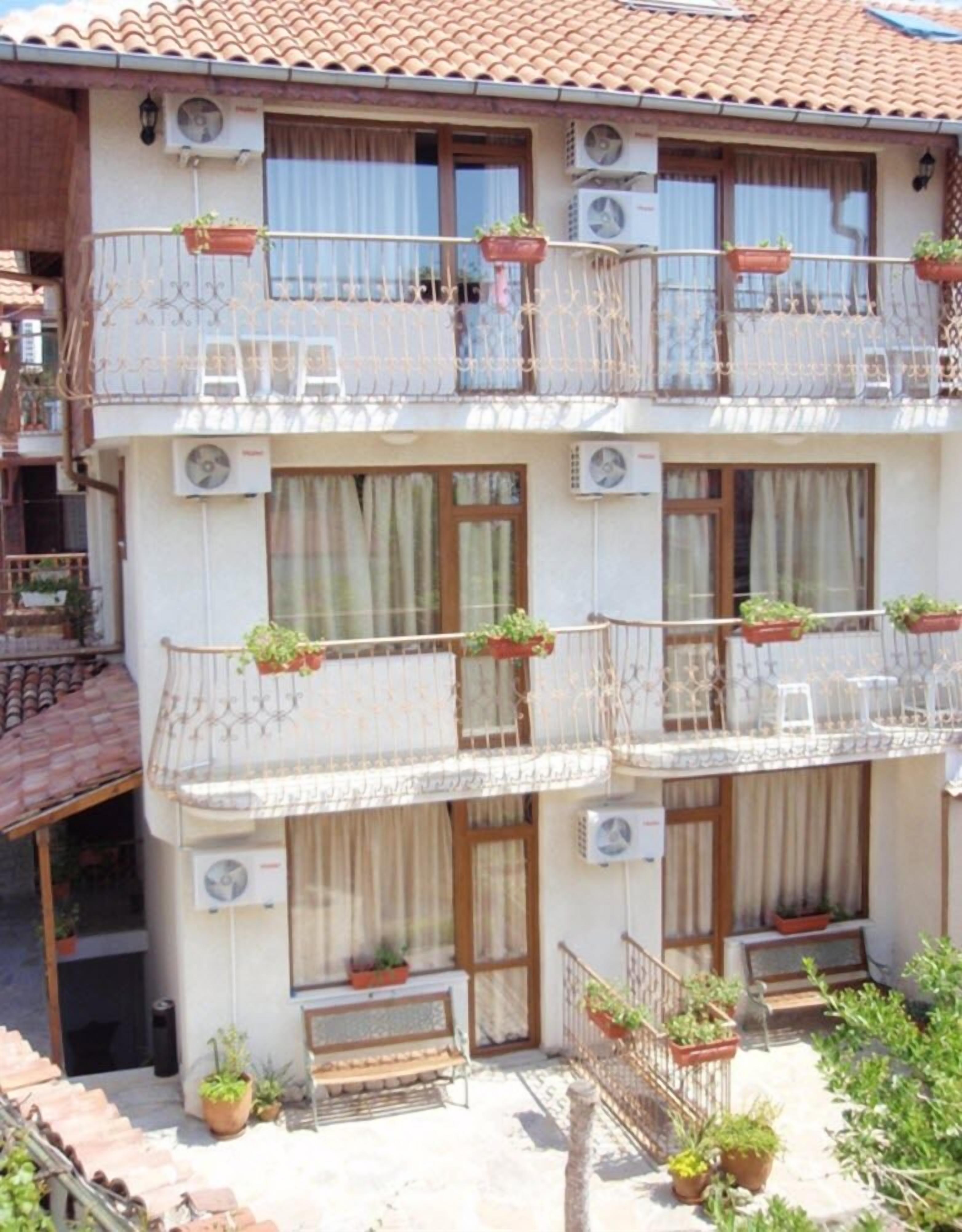 A multi-story building with balconies, air conditioning units, and potted plants.