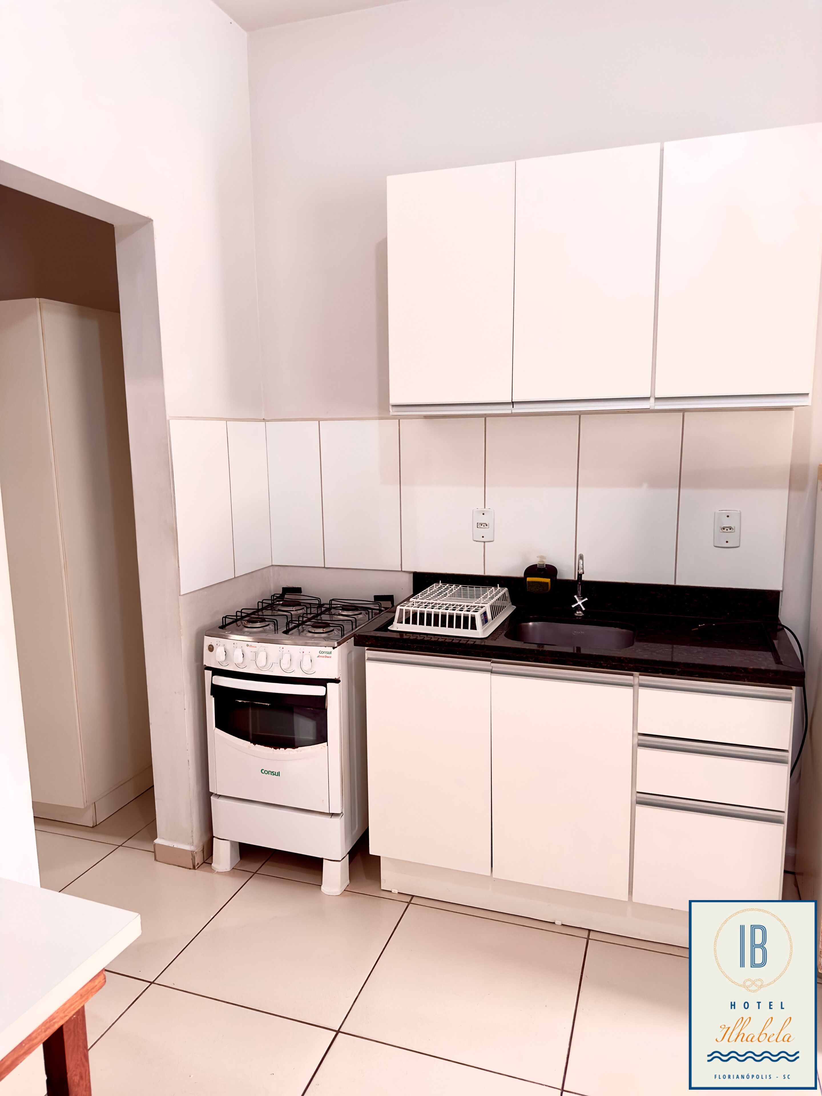 Una cocina moderna con armarios blancos, estufa a gas, horno y encimera negra.