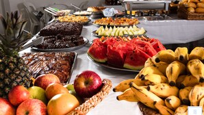 Una mesa de buffet con distintos alimentos, como frutas, pasteles y repostería.