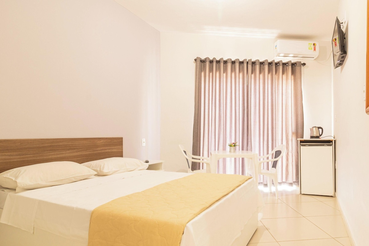 Ein Hotelzimmer mit Bett, einem kleinen Tisch, Stühlen, einem Schreibtisch und einem Wasserkocher.