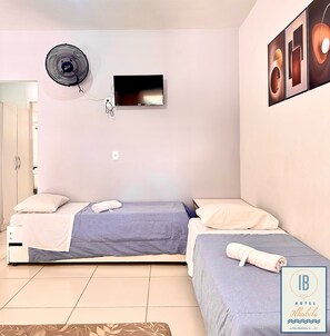 Ein Schlafzimmer mit zwei Betten, einem Fernseher, einem Wandventilator und einer Tür.