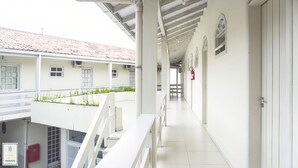 Un pasillo con paredes blancas y techo de baldosas, que conduce a varias habitaciones con ventanas y puertas.