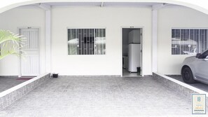 Ein Hotel Eingang mit bepflasterter Auffahrt, einem Topfpflanzen und einem parkenden Auto.