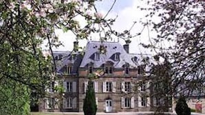 Un grand bâtiment historique à la façade symétrique, doté de nombreuses fenêtres et d’une entrée centrale.