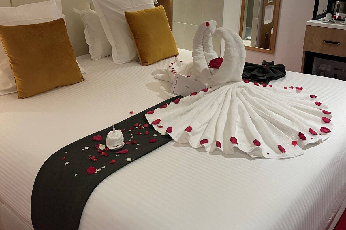 A hotel room with a large bed, a headboard, a bedside table, a mirror, and a nightstand.