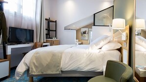 Una camera d'albergo con un letto, una scrivania, una televisione e uno specchio.