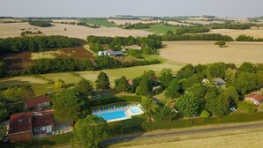 Vista aérea de una propiedad rural con piscina, varias casas y campos extensos.