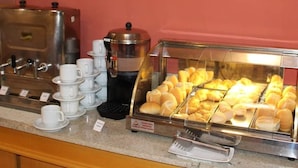Ein Buffet mit Kaffeeautomaten, einer Kaffeekanne und einer Vitrine mit Gebäck.