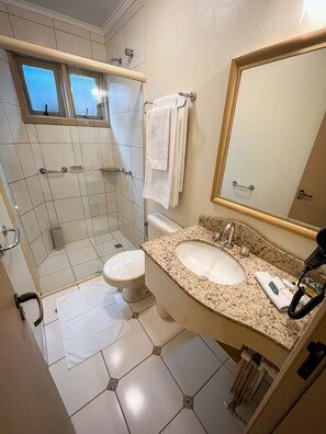 Een badkamer met douche, toilet, wastafel en een spiegel.