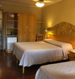 Een hotelkamer met twee bedden, een kledingkast, een bureau en een nachtkastje.