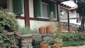 Ein Gebäude mit grünen Fensterläden, steinernen Stufen und Blumentöpfen.