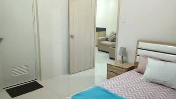 A bedroom with a bed, bedside table, lamp, and a mirror.