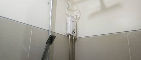 A shower with a handheld showerhead and a wall-mounted control panel.