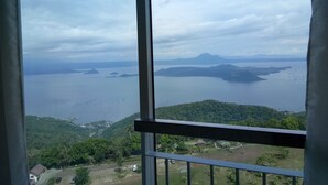 A view from a balcony overlooking a body of water with distant islands, surrounded by greenery.