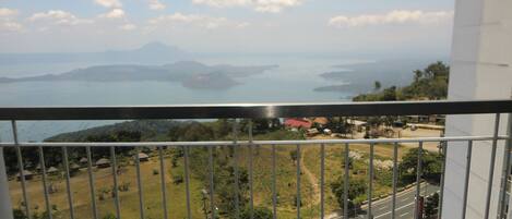 A balcony with a view of a road, parked cars, and distant islands.
