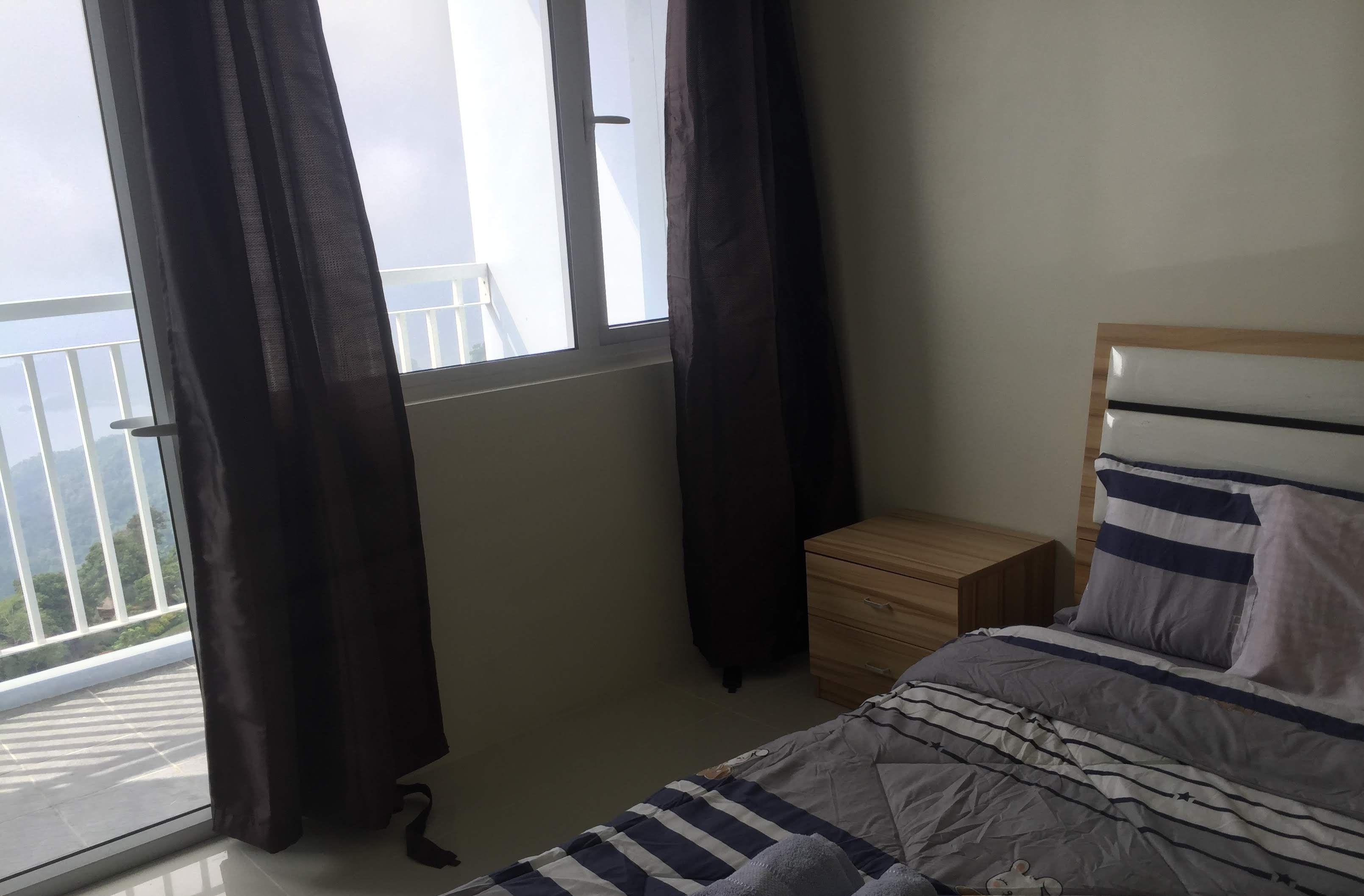 Een slaapkamer met een bed, nachtkastje en een raam met gordijnen.