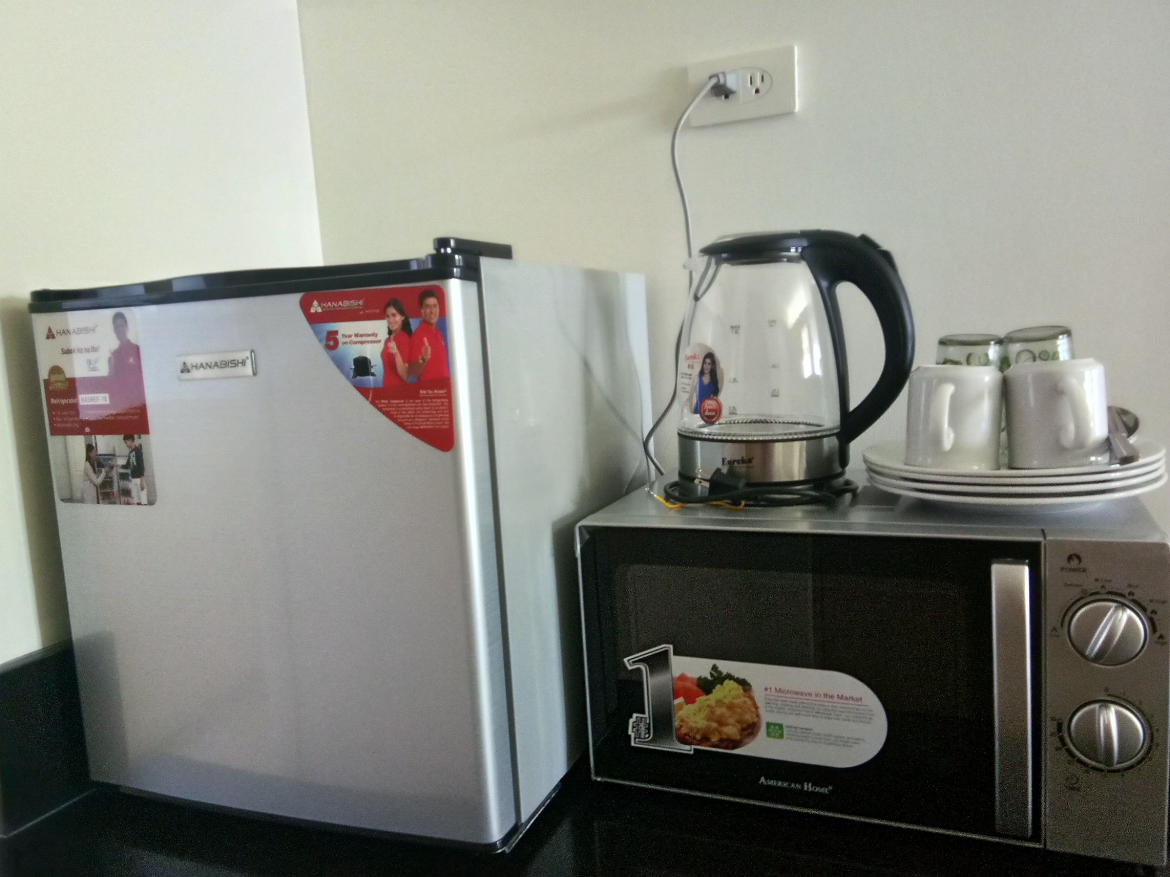 A compact kitchenette with a refrigerator, a coffee maker, and a microwave.