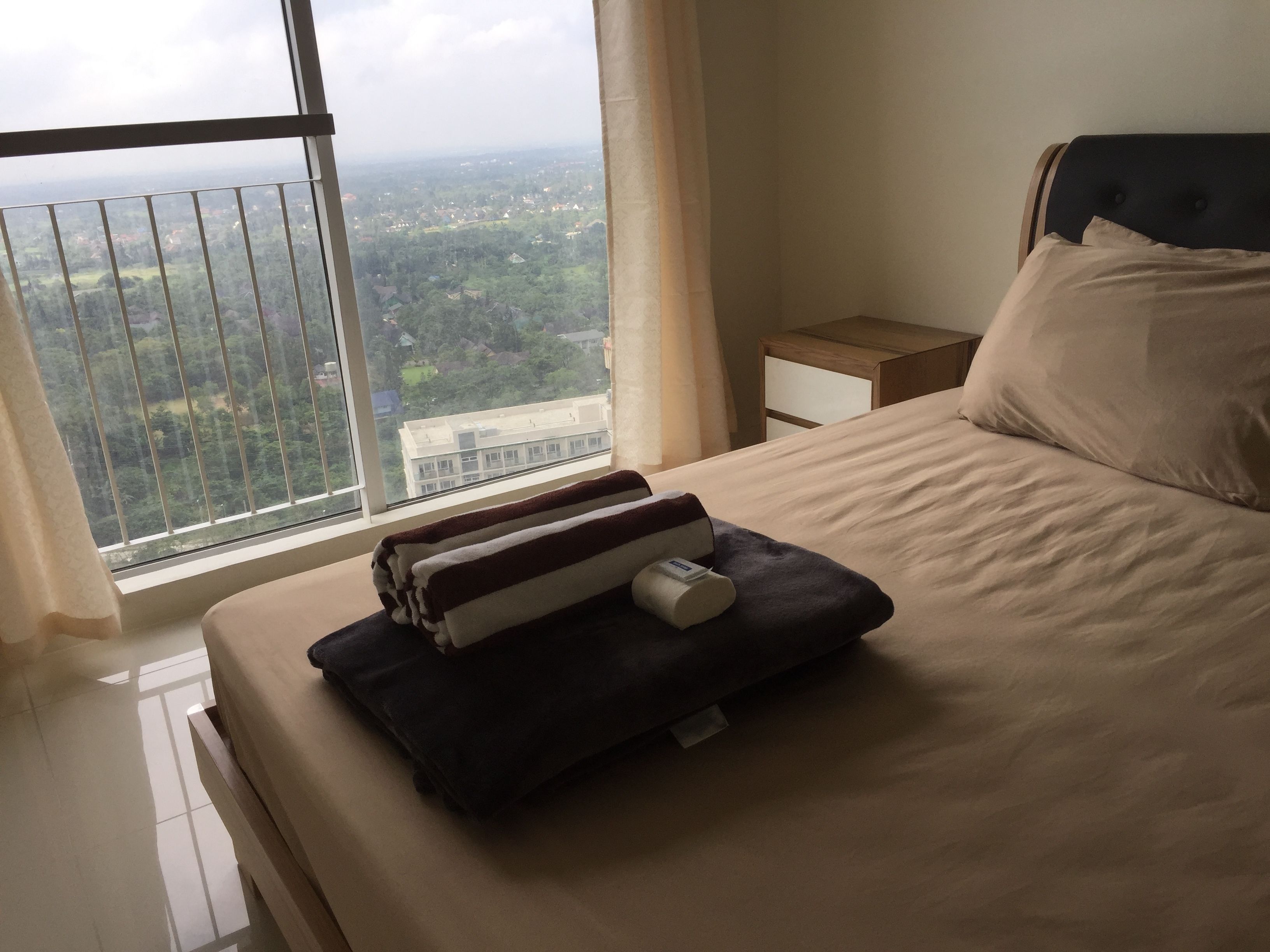 Habitación de hotel con un ventanal amplio que ofrece vistas a un paisaje urbano y áreas verdes.