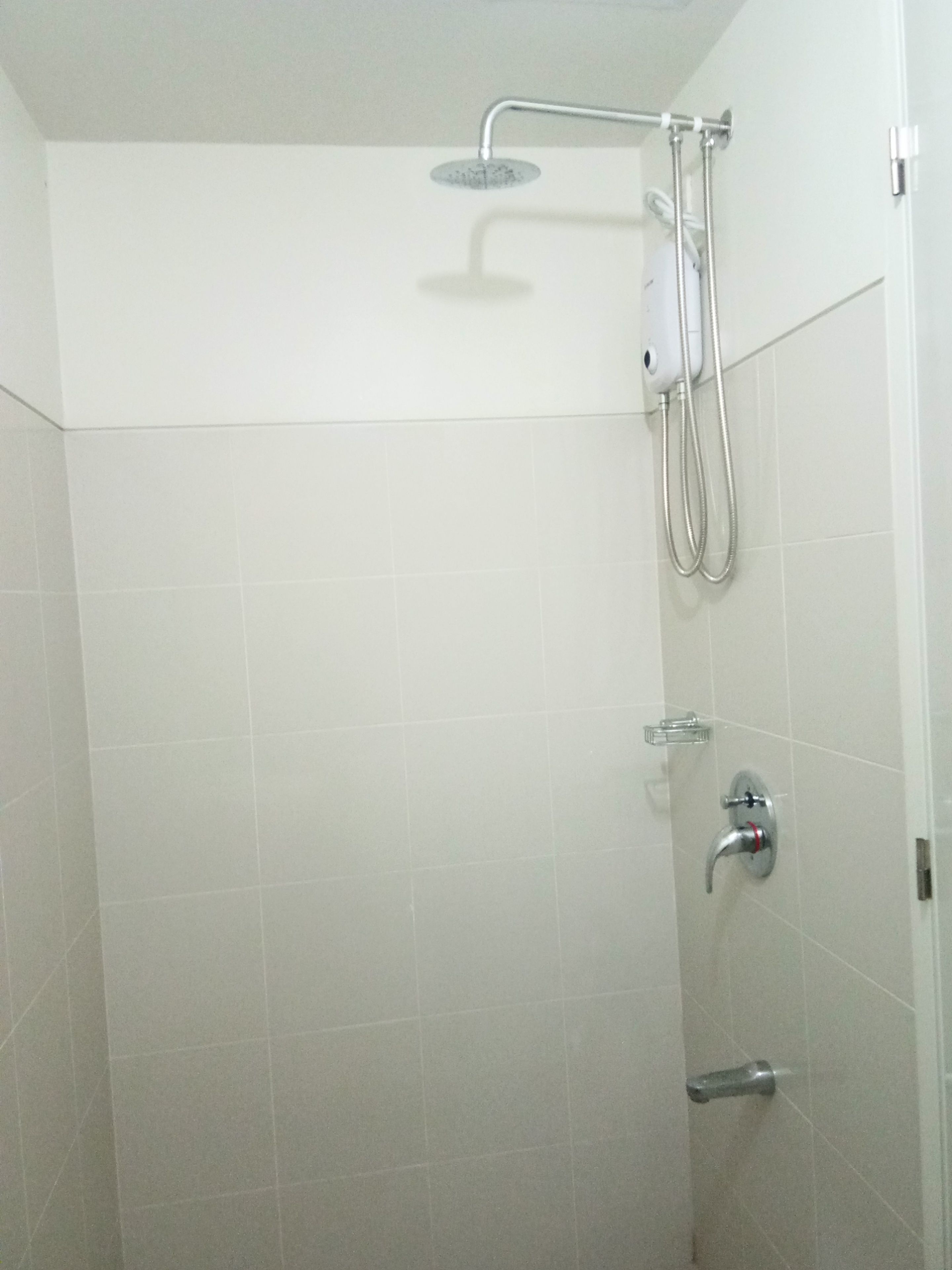 Eine Dusche mit Handbrause und am Wand montiertem Wasserhahn.