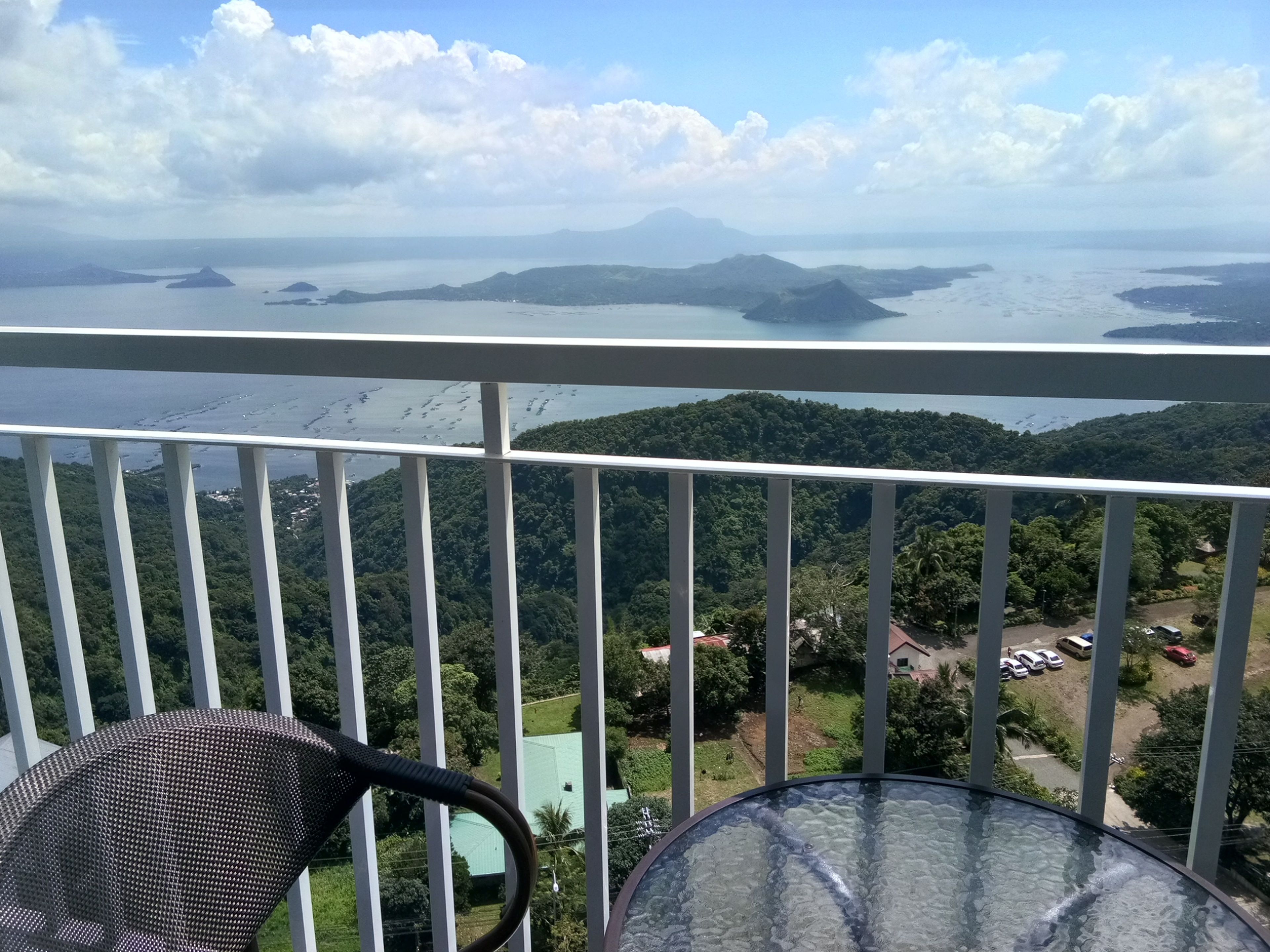 A balcony with a view of a mountainous landscape and a body of water.