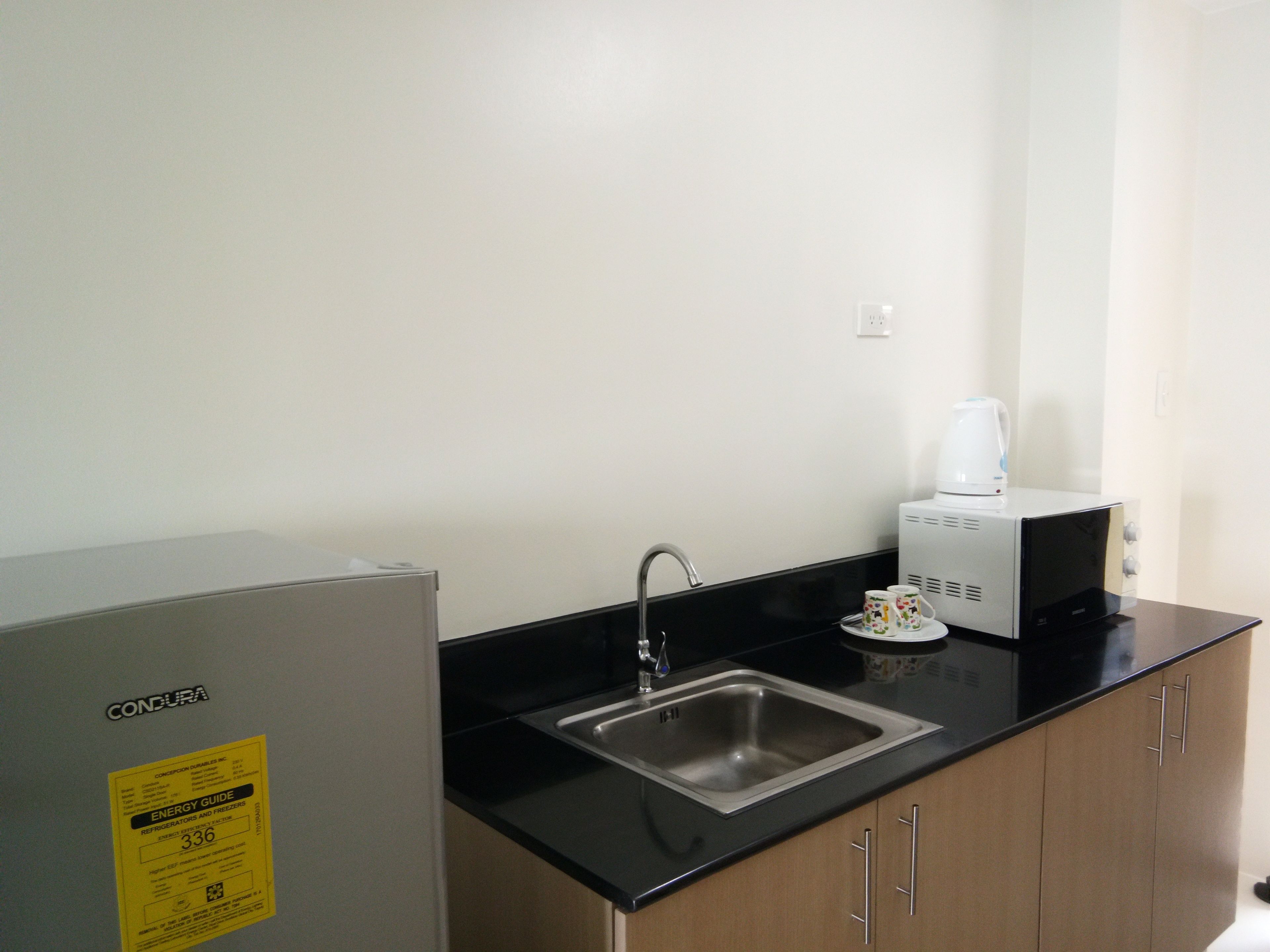 A compact kitchen with a stainless steel sink, a coffee maker, and a refrigerator.