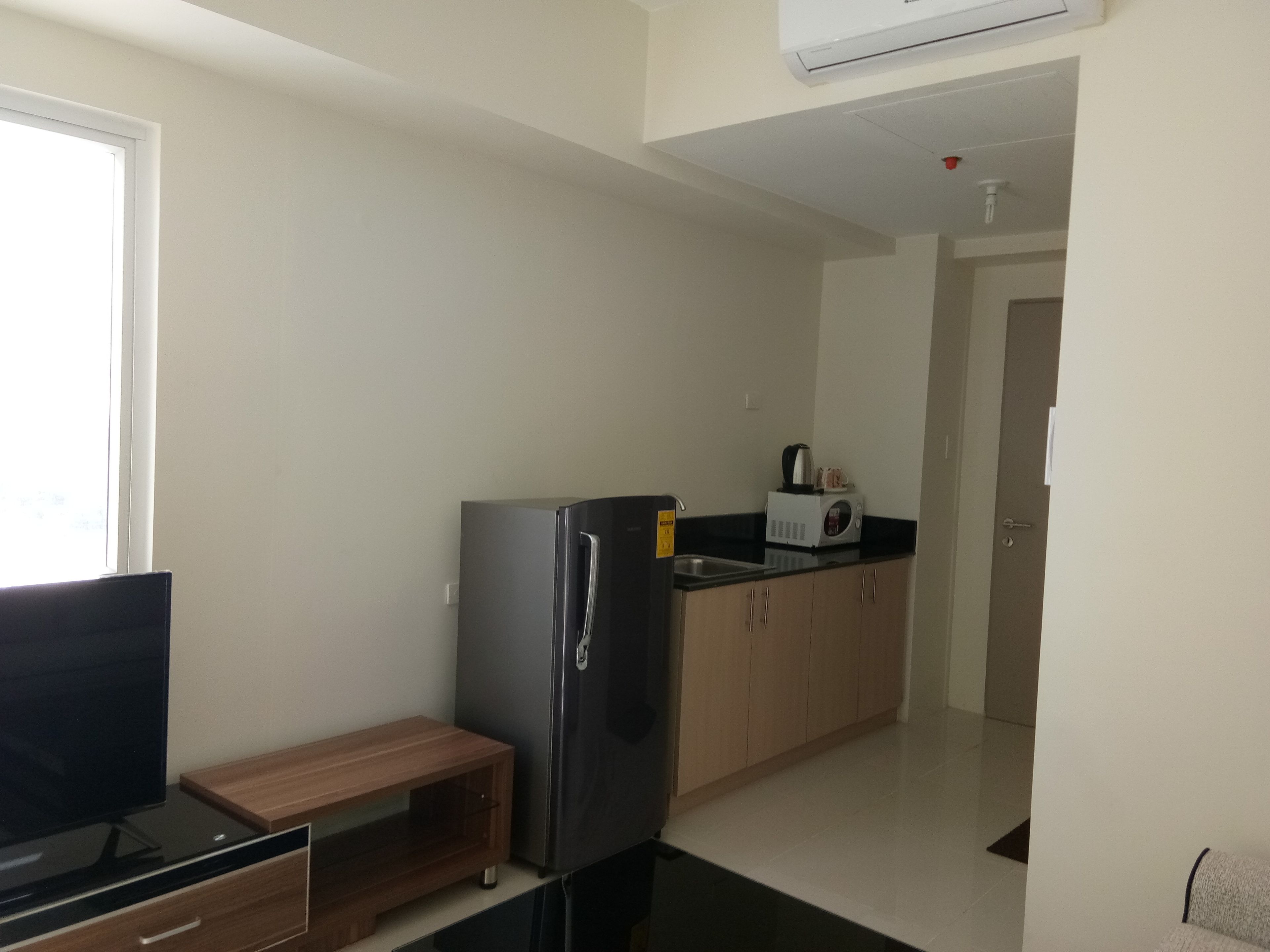 Una cocina moderna con refrigerador, microondas y una pequeña mesa de madera.