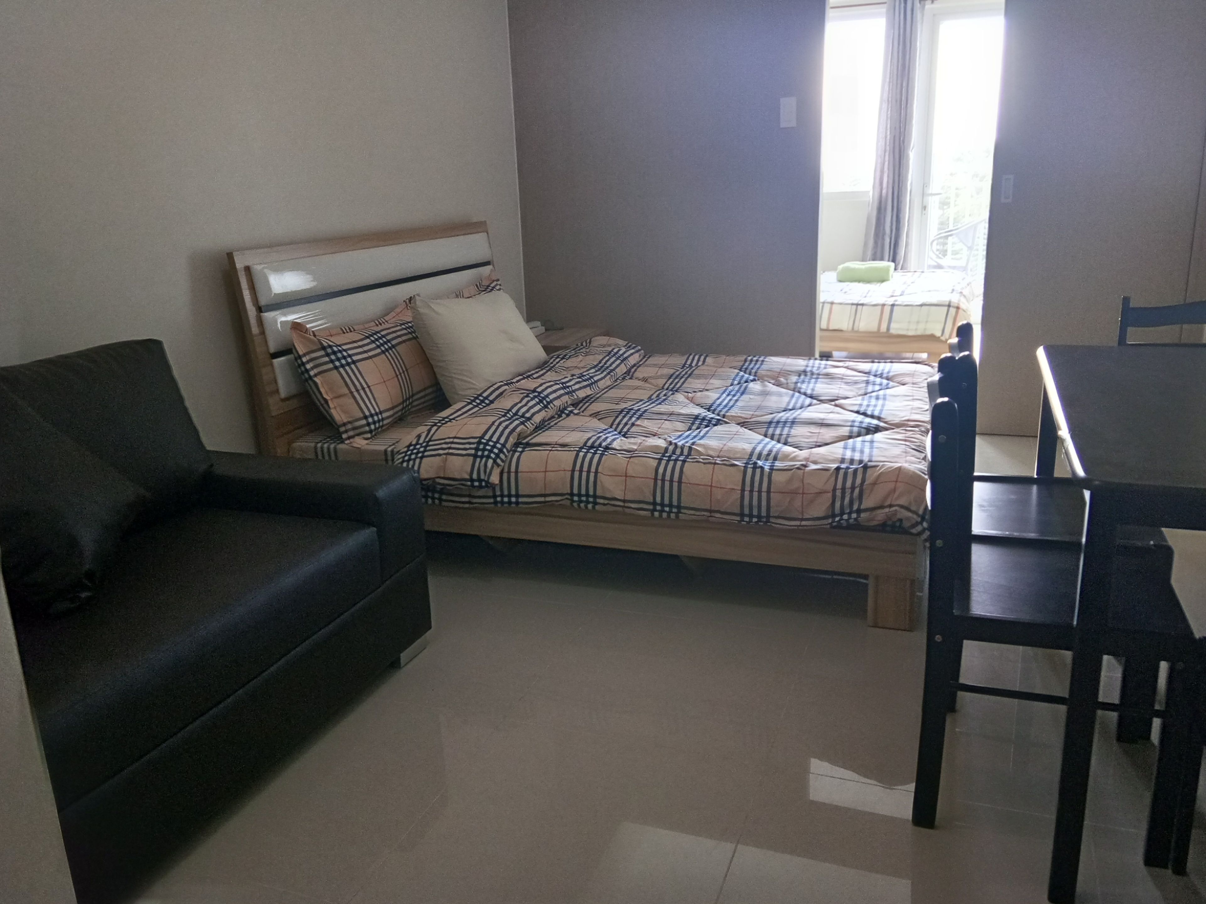 A bedroom with a bed, a sofa, and a desk.