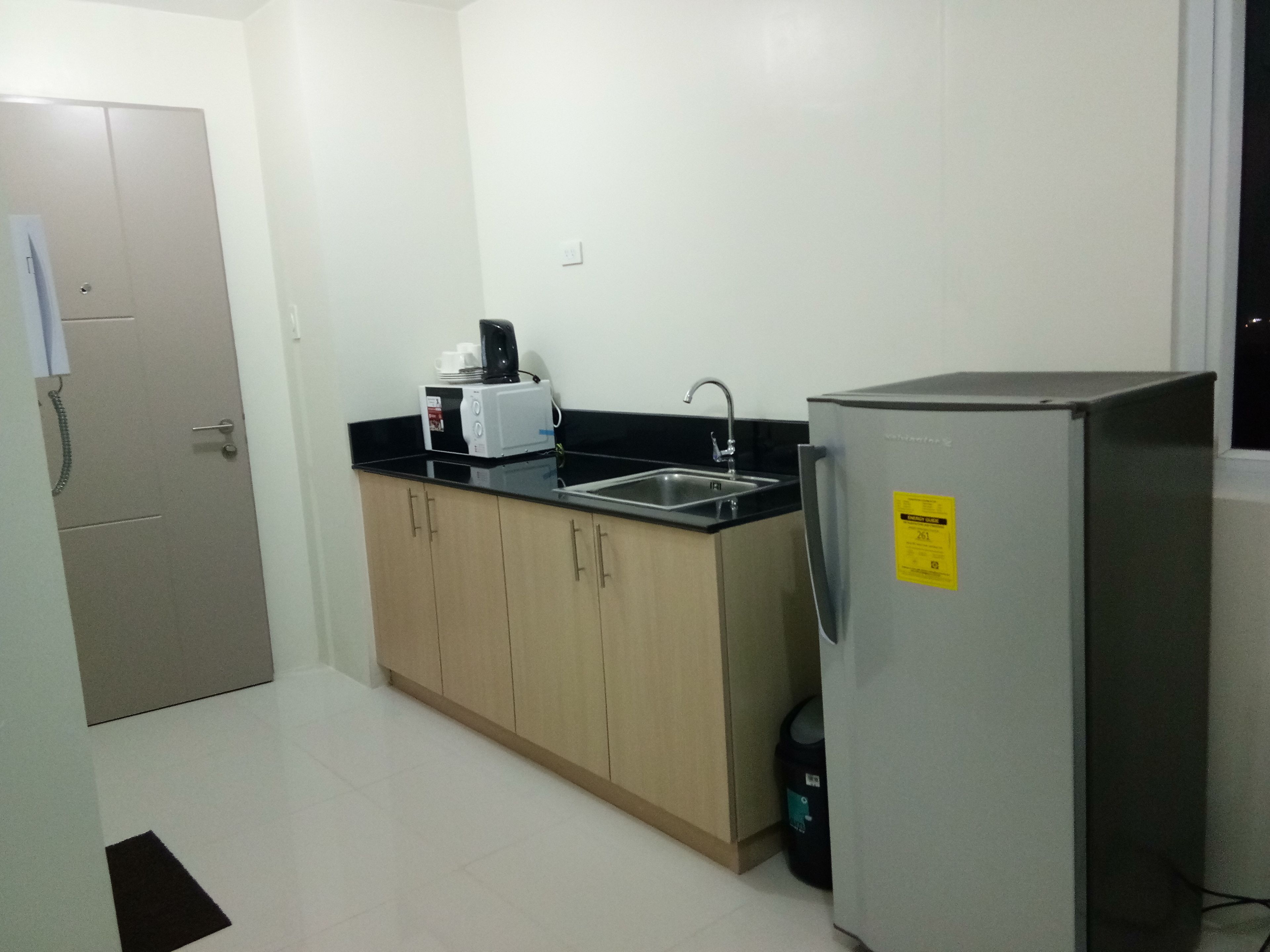 A small kitchenette with a refrigerator, a sink, and a microwave.