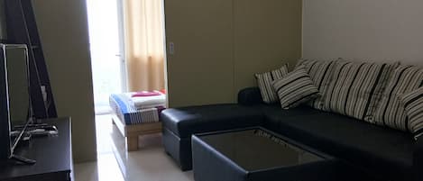 A modern living room with a sectional sofa, a small coffee table, and a TV on a stand.