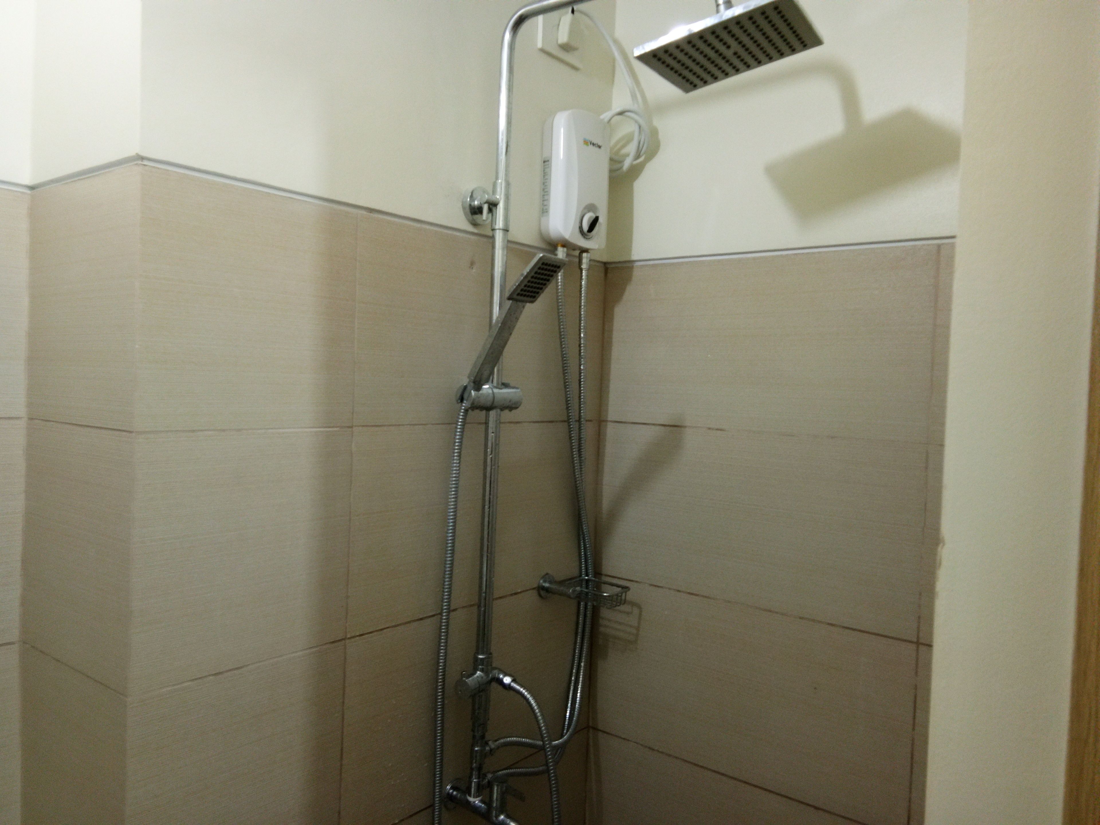 Una ducha con cabezal de ducha manual y panel de control en la pared.