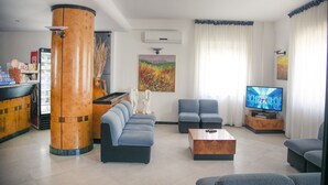 A modern living room with a sofa set, a coffee table, a television, and a large pillar. - Hotel Pineta (Vico del Gargano)