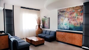 A modern living room with a sectional sofa, a coffee table, and a large abstract painting on the wall. - Hotel Pineta (Vico del Gargano)