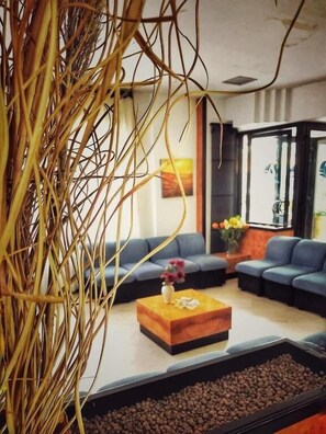 A modern living room with a sectional sofa, a coffee table, and a decorative plant. - Hotel Pineta (Vico del Gargano)