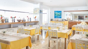 A dining area with tables set for a meal, featuring white chairs and yellow tablecloths. - Hotel Pineta (Vico del Gargano)