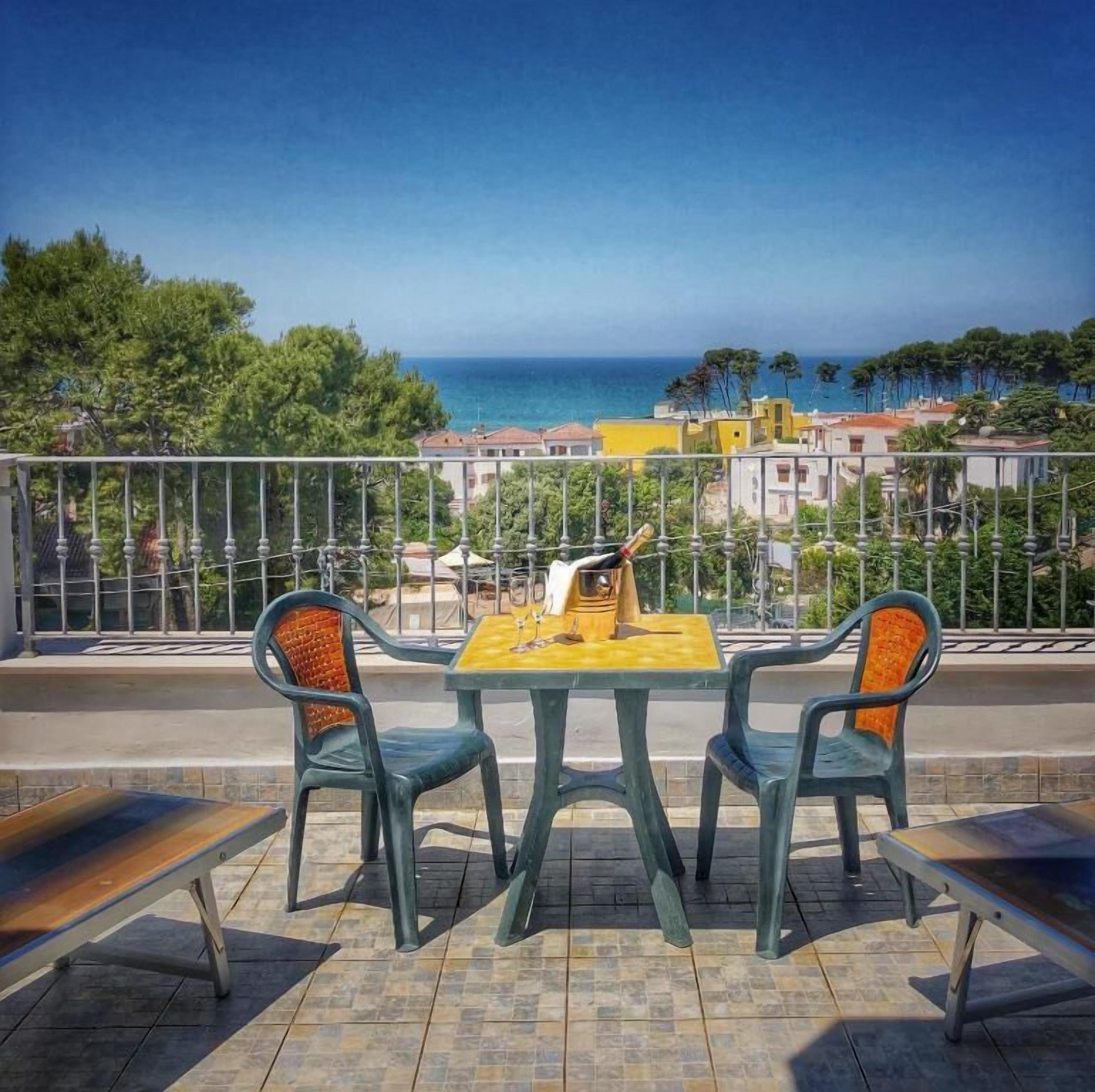 Une terrasse avec une table et des chaises donnant sur une vue panoramique de la côte.