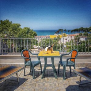 A terrace with a table and chairs overlooking a coastal view. - Hotel Pineta (Vico del Gargano)