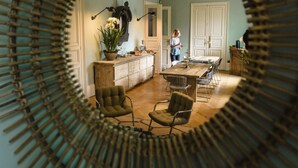 A dining area with a wooden table and four chairs, a potted plant, and a kitchen area with cabinets and a stove.