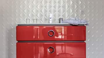 Une coiffeuse rouge surmontée d’un miroir rond, le tout placé devant un mur à texture.
