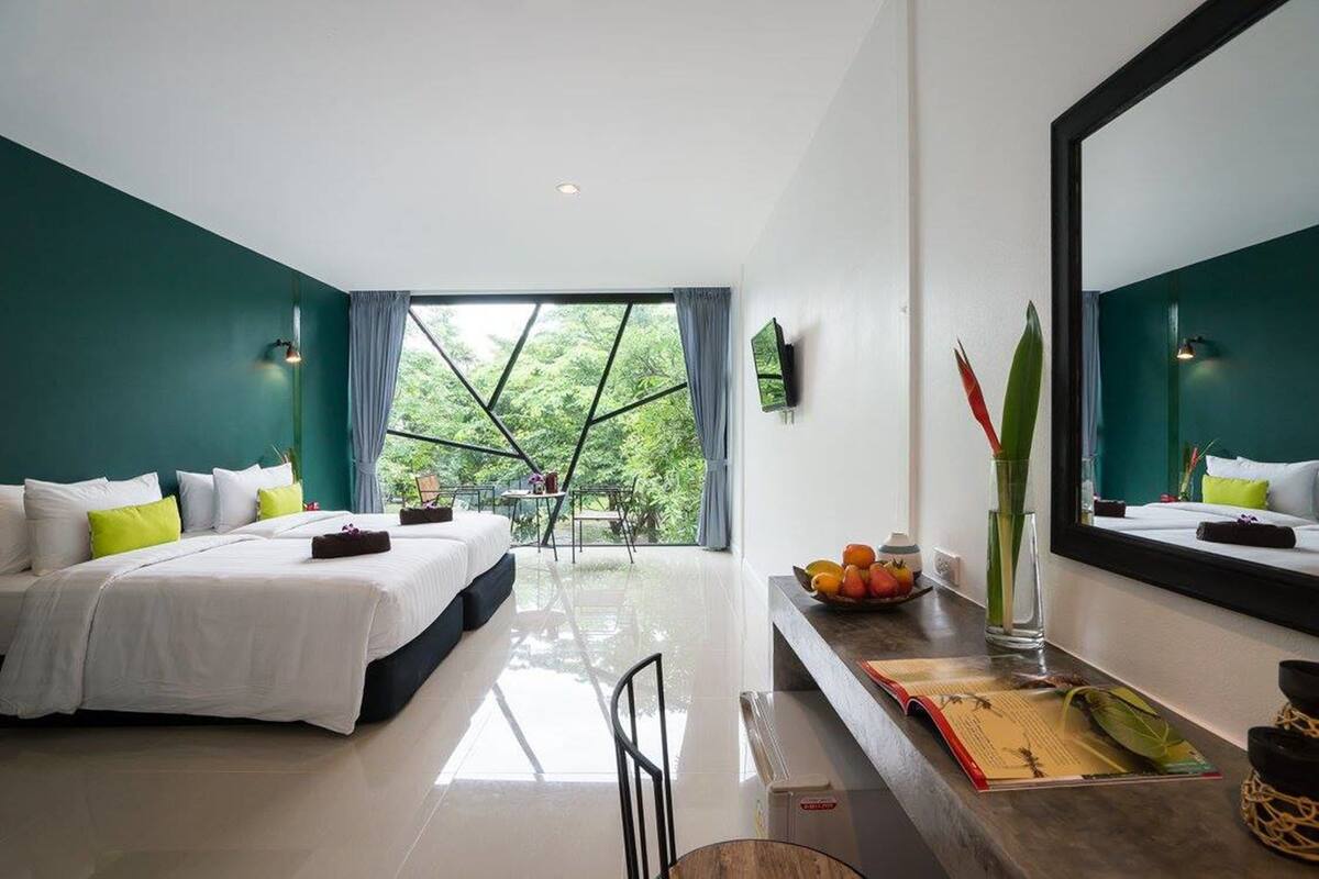 Un hotel moderno con una cama grande, un escritorio y vistas a la vegetación por la ventana.