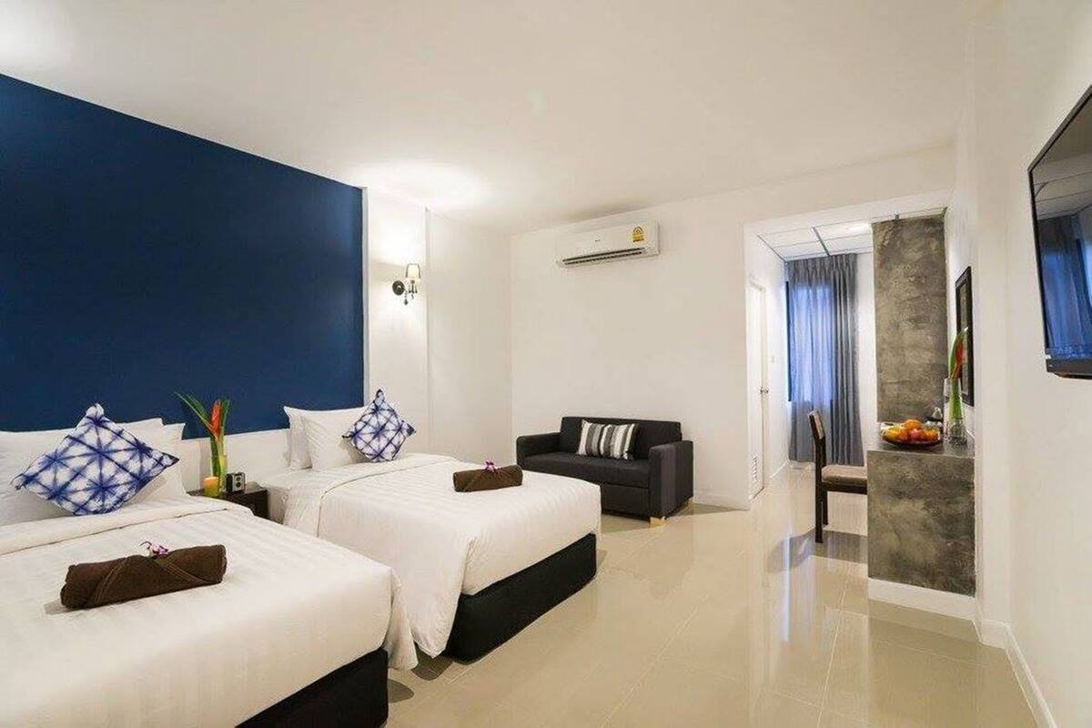 Habitación de hotel con dos camas, un sofá, un espejo y un frutero.