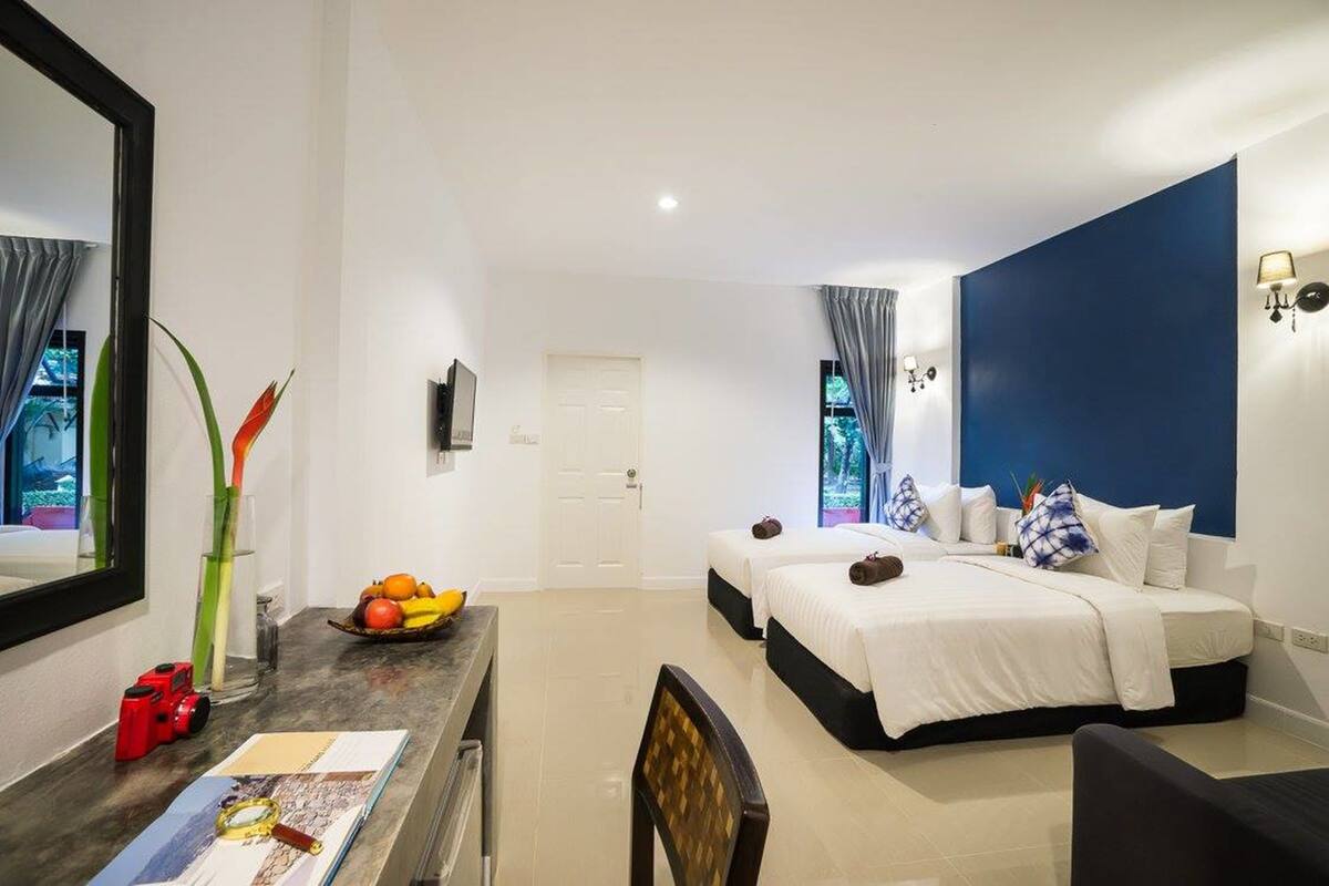 Una habitación de hotel con cama, escritorio, silla, espejo y ventana con cortinas.