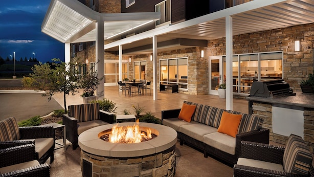An outdoor patio with a fire pit, seating area, and a barbecue grill.