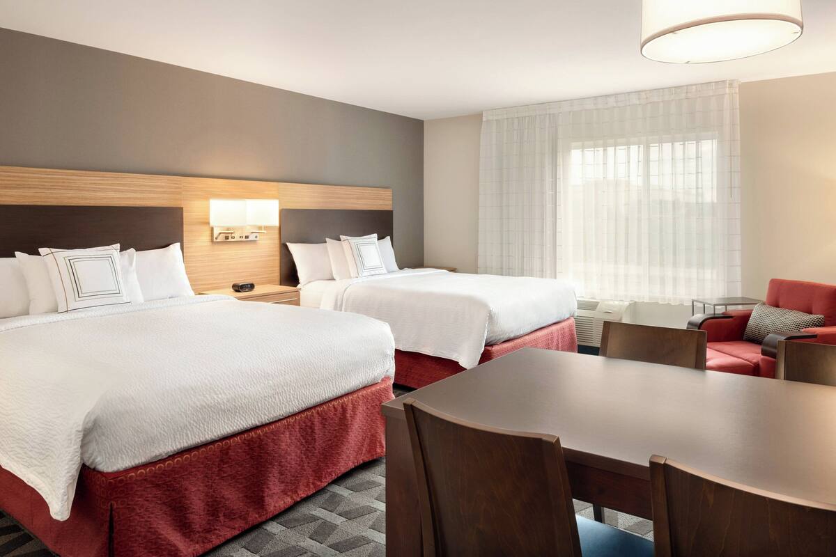 Een hotelkamer met twee bedden, een eettafel en een bank.