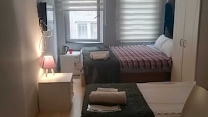 A compact bedroom with two beds, a wardrobe, a desk with a lamp, and a window with blinds. - Bufes Hotel (Istanbul)