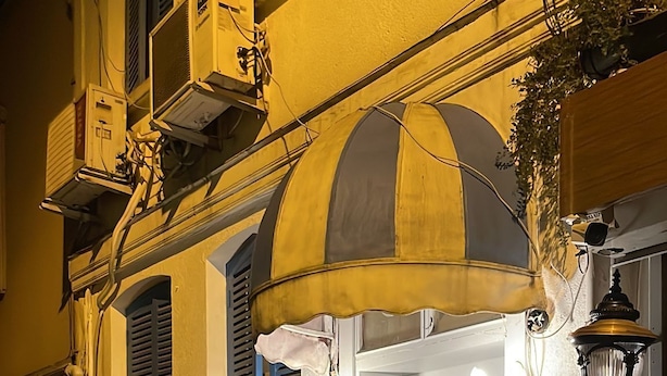 A hotel entrance with a sign reading "BUFFES HOTEL," a door with a number "22," and a small outdoor seating area with a table and chairs. - Bufes Hotel (Istanbul)