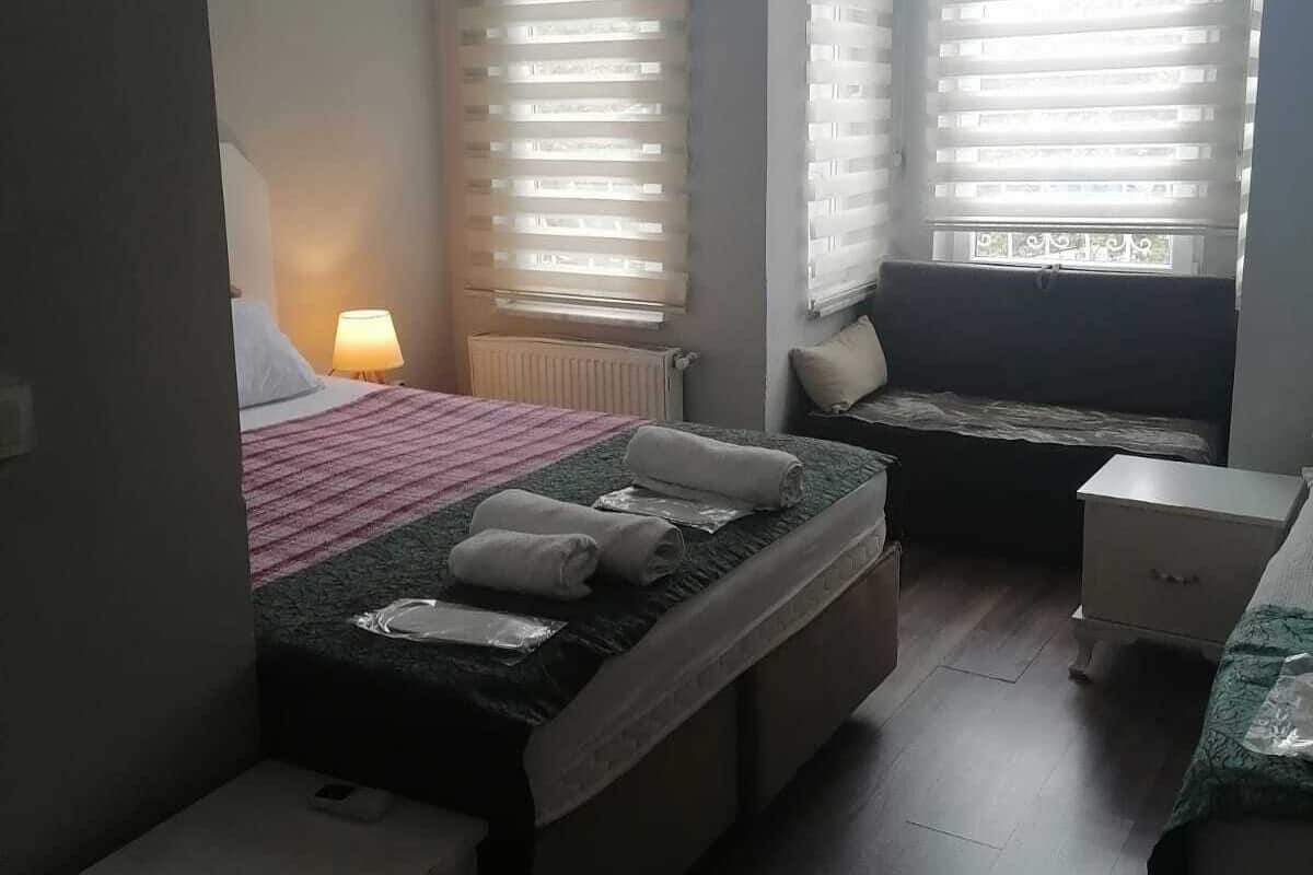 A bedroom with a bed, bedside tables, a window with blinds, and a radiator.