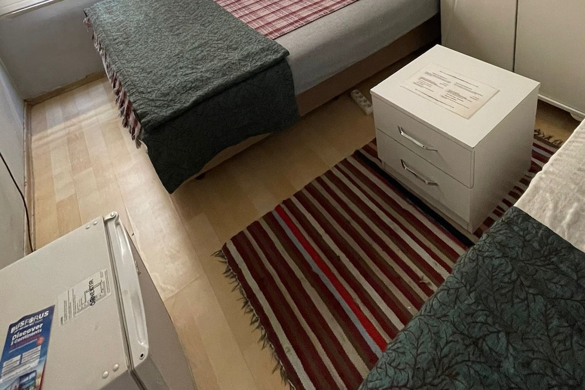 A small, compact room with a bed, a wardrobe, a desk, and a radiator.