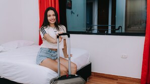 A person sitting on a bed with a suitcase and a walking stick. - Residencial Marina House (La Banda de Shilcayo)