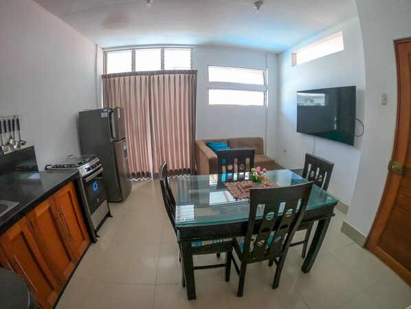A compact living space with a kitchen, dining area, and a TV mounted on the wall.