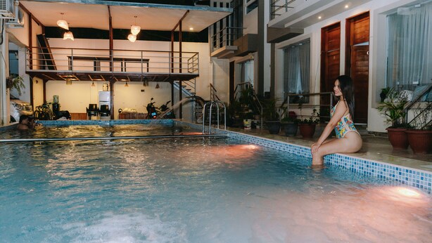 An indoor swimming pool with a tiled edge, a metal ladder, and a staircase leading to an upper level. - Residencial Marina House (La Banda de Shilcayo)